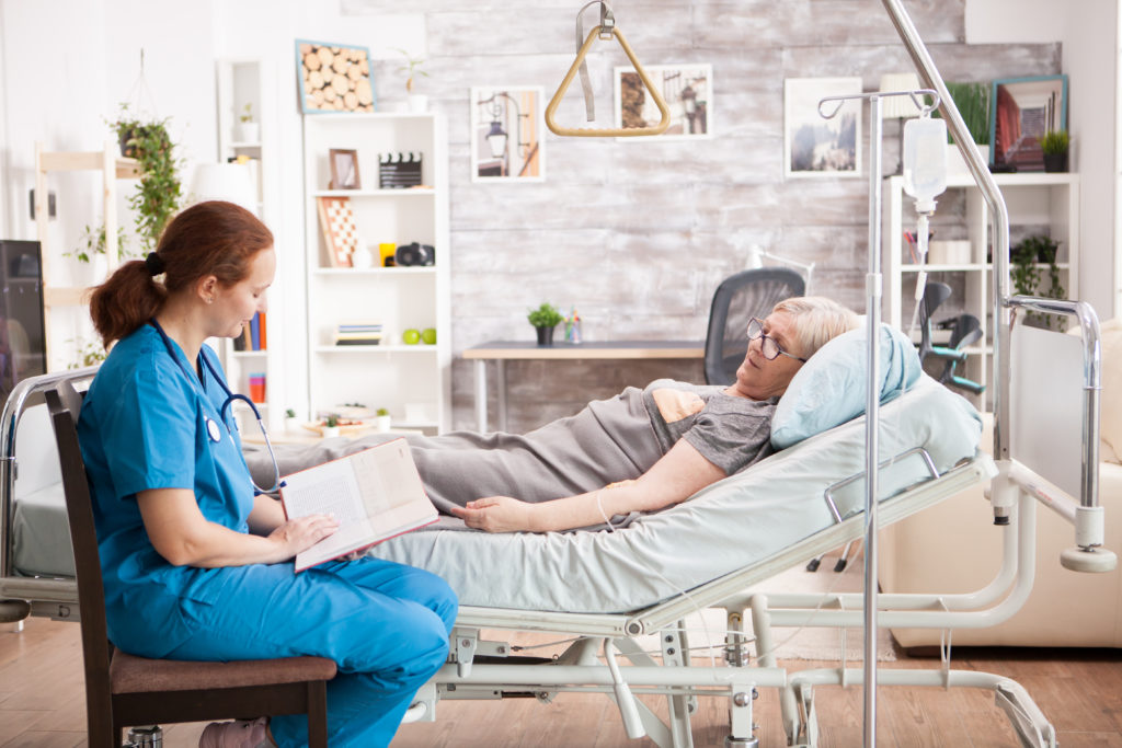 caregiver reading a book to her patient