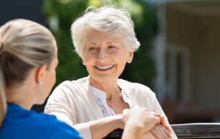 senior woman on wheelchair smiling at her caregiver