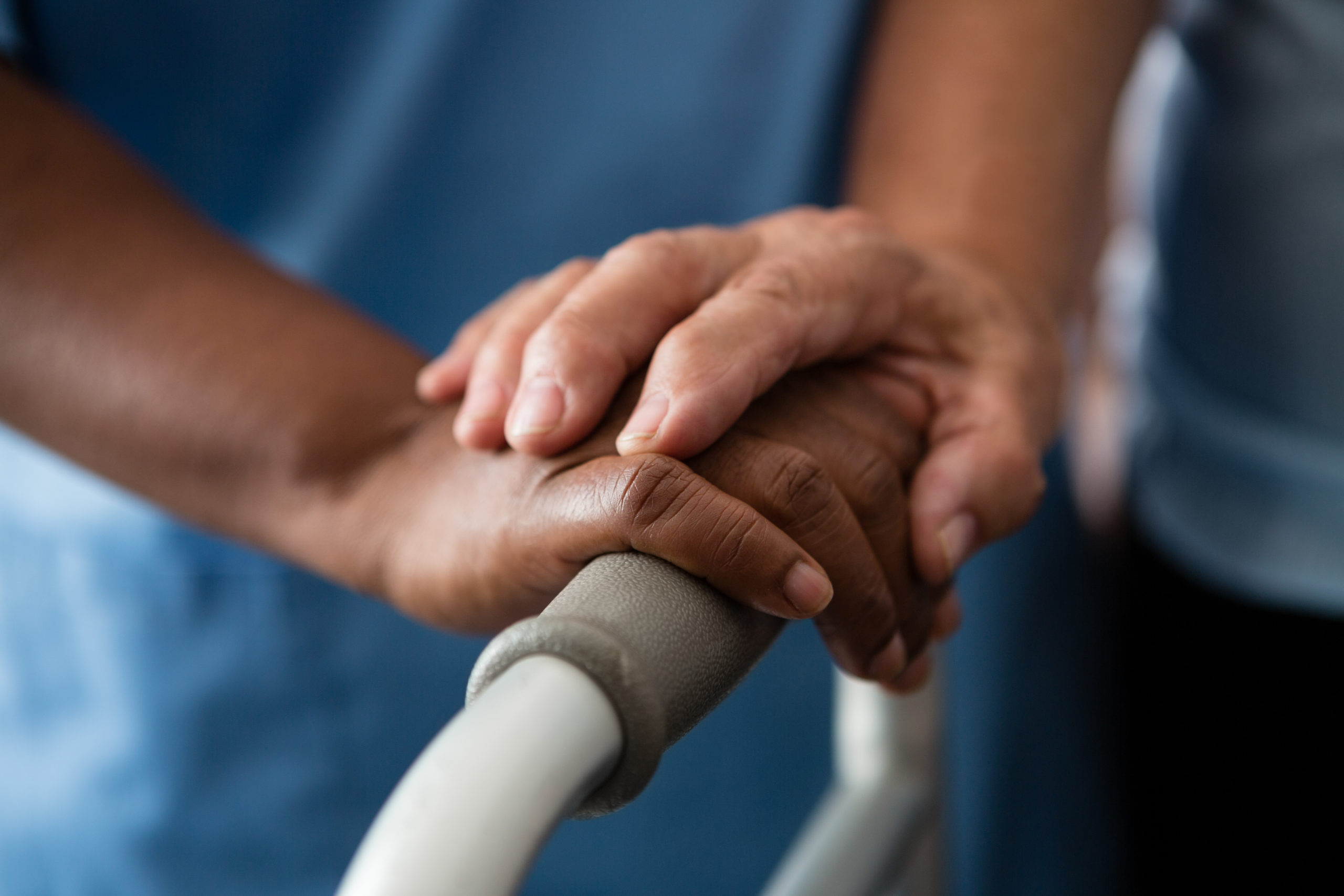 Hands of nurse and senior woman holding walker in nursing home