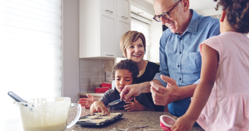 Family caregiver assists her children and her elderly father make cookies during the holidays