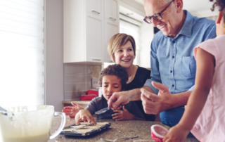 Family caregiver assists her children and her elderly father make cookies during the holidays