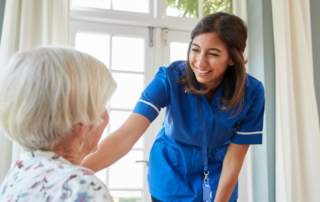 A home health care professional enjoys her job as she helps a senior patient.