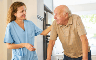 Caregiver smiling at senior man using a walker.