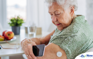 A senior woman uses her smartphone to check her glucose monitor, a tool that can be extremely helpful for diabetes care.