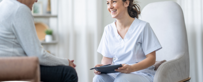 A woman smiles and enjoys her caregiving job as she writes notes down with a client.