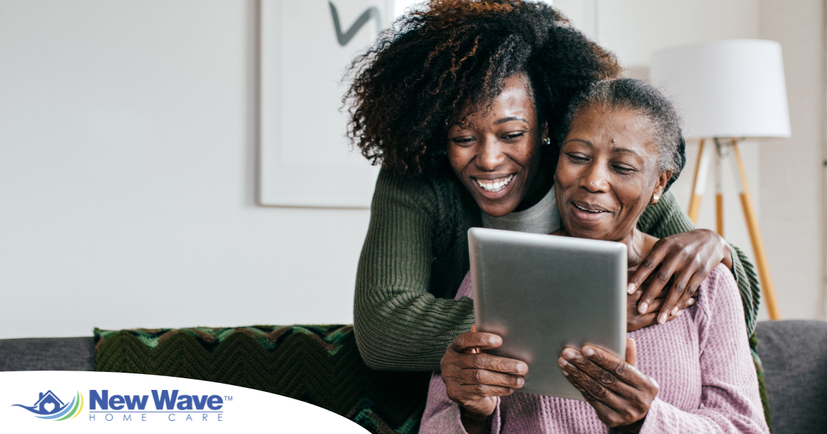 A caregiver helps a senior with her tablet, representing the rise of technology in home care.
