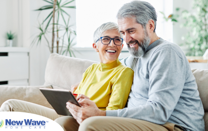 A senior couple smiles while looking at a laptop, showing how online resources can help family caregivers.