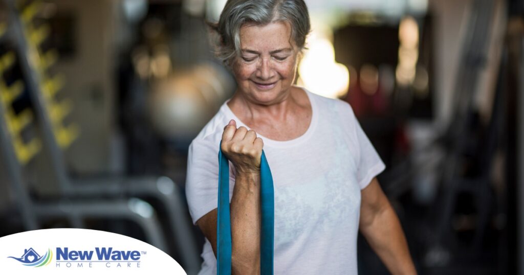 An older woman uses a resistance band to exercise, representing how staying active can help older adults keep their blood pressure in a healthy range.
