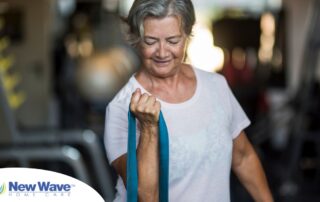 An older woman uses a resistance band to exercise, representing how staying active can help older adults keep their blood pressure in a healthy range.
