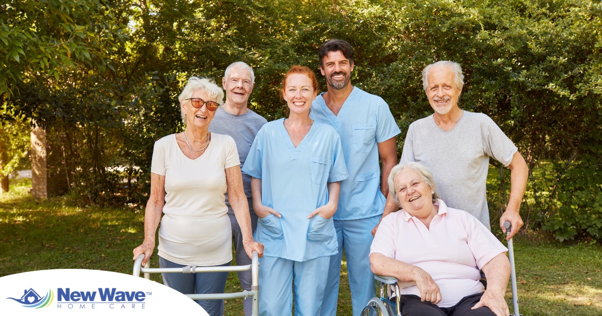 2 caregivers and seniors smile while in a group representing how caregivers can facilitate socialization.
