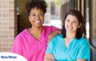 2 caregivers smile representing the good attitude that can allow home care professionals to collaborate.
