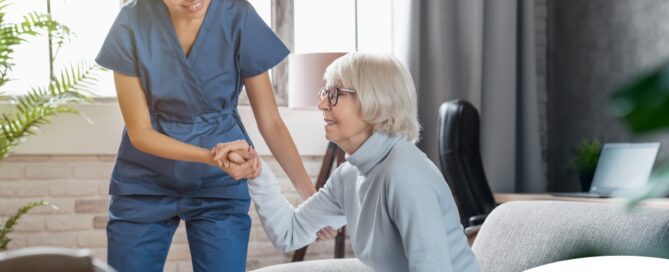 A caregiver demonstrates her caregiver skills by helping an older adult get up.