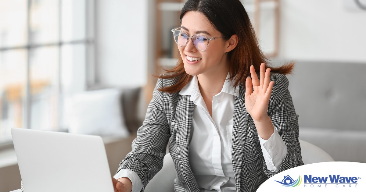 A well-dressed woman smiles and says hi on a videoconference, representing a candidate who is well-prepared for a caregiver interview.