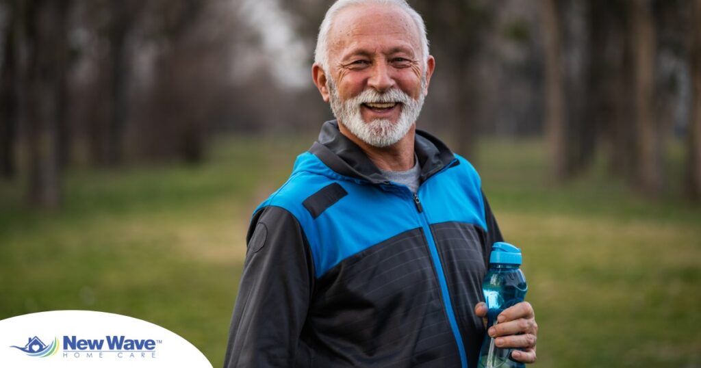 An older man smiles with a water bottle while exercising, representing the benefits of encouraging exercise when caring for seniors at home.
