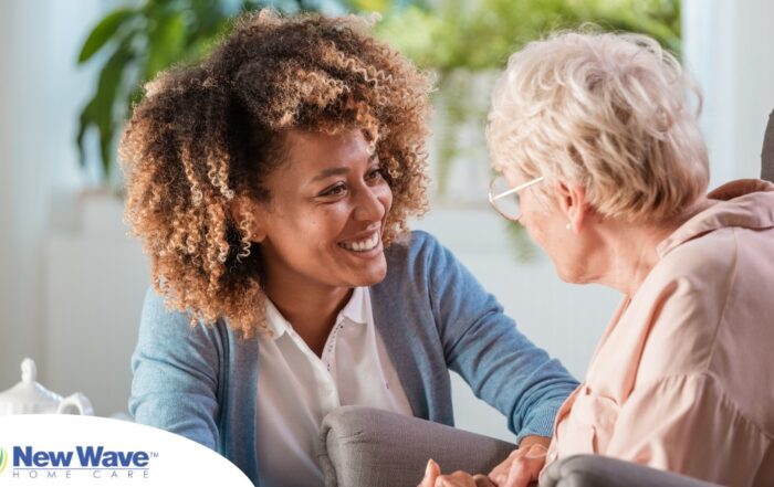 A caregiver smiles at an older client in a chair, representing the joy that can come from a healthy work-life balance.