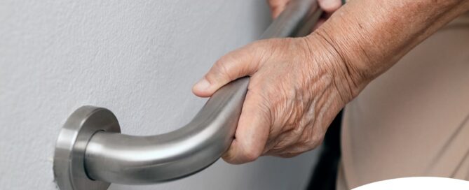 An older adult uses a grab bar representing one of the home modifications that is helpful for fall prevention for elderly adults.