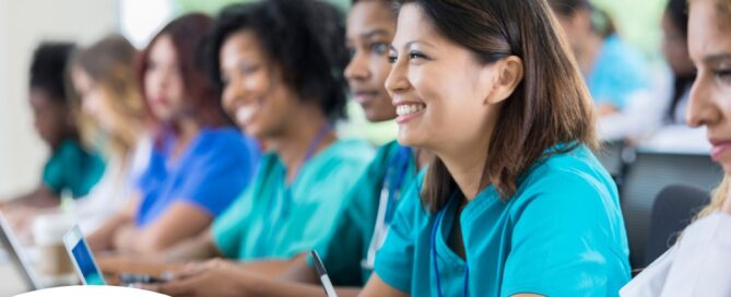 Several students in scrubs happily attend a class, representing caregiver training.