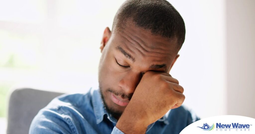 A man tiredly rubs his eyes, representing the exhaustion that can come with family caregiving.