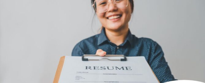 A woman happily hands in a resume, representing a successfully written caregiver resume.