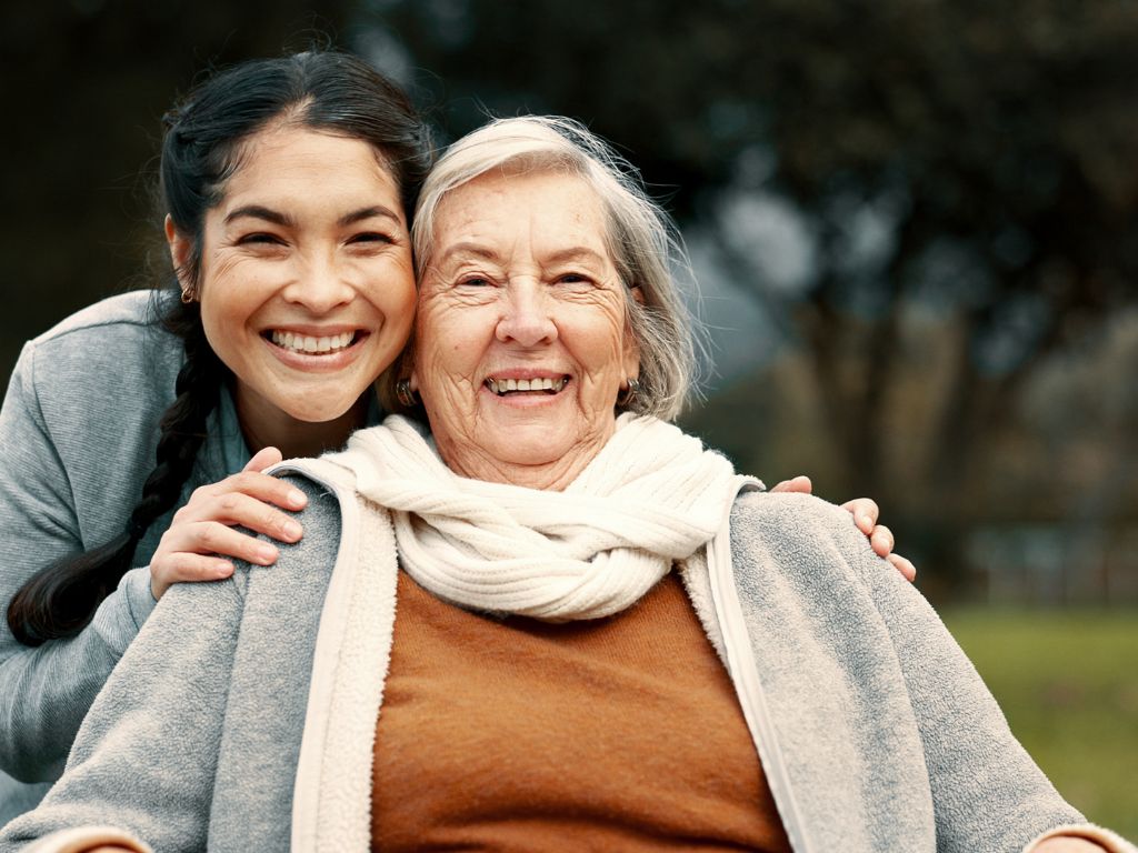 Caregiver and senior woman smiling together outdoors, representing Alzheimer’s and dementia care in Redondo Beach