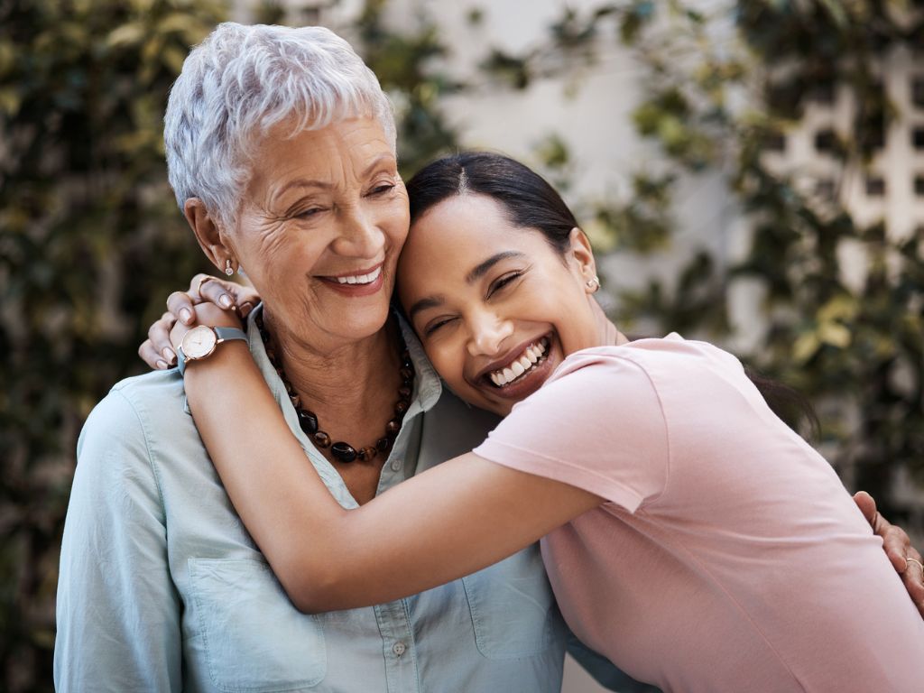 A smiling senior woman and her caregiver sharing a warm embrace at home, reflecting compassionate personal care in Torrance.