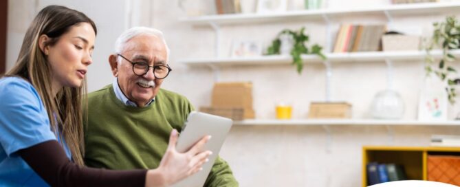 Home caregiver assisting senior man to use telehealth and senior care